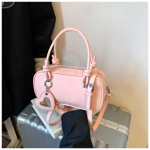 Détail du sac à main rose en similicuir avec poignées nouées et breloque miroir cœur