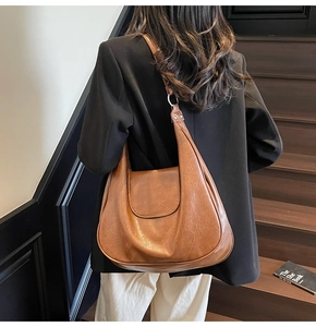 Detail of vintage brown oil wax leather hobo bag with metal ring and large capacity