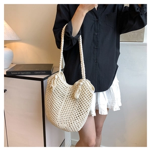 Detail of hollow-out straw tote bag featuring tassel accents and a woven mesh pattern