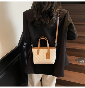 Détail du sac seau beige à motif géométrique avec bordure en cuir marron et bandoulière