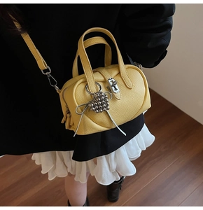 Détail du mini sac jaune en cuir grainé avec breloque cœur et finitions métalliques argentées