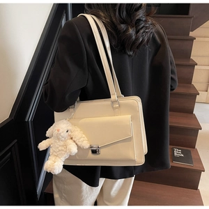 Femme portant un sac cabas en cuir crème avec détail de charm lapin en peluche