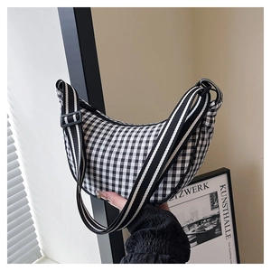 Detail of black and white gingham crescent bag with a striped adjustable shoulder strap