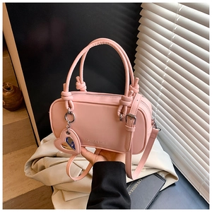 Détail du sac Boston rose en cuir PU avec breloque cœur et bandoulière réglable