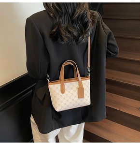 Sac fourre-tout motif blanc cassé et marron porté par un mannequin sur des escaliers en bois