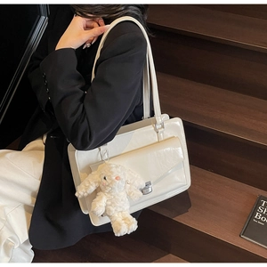 Détail d'un sac cabas en similicuir crème avec fermoir rotatif argenté et breloque lapin