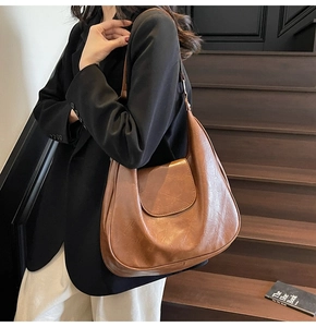 Brown vintage hobo bag styled with a black suit in a minimalist indoor setting