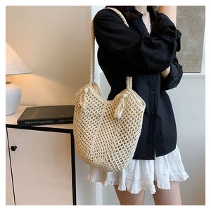 Close-up of beige crochet tote bag with mesh texture and decorative tassels