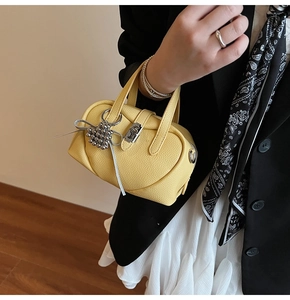 Détails de la texture du cuir jaune et du fermoir argenté sur le mini sac à main