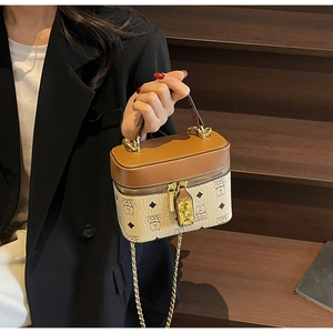 Detail of a beige bucket bag with bear patterns, brown leather trim and gold chain strap