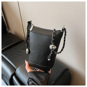 Détail du sac seau en cuir noir grainé avec chaîne argentée et breloque boule métal