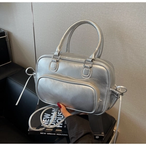 Macro detail of silver metallic textured crossbody bag with zip pocket and dual handles