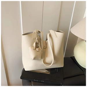 Detail of cream lychee leather tote bag with a matching mini charm pouch accessory