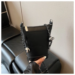 Détail d'un sac seau noir en cuir grainé avec bandoulière chaîne et ornements argentés