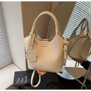 Detail of off-white lychee grain leather bucket bag with puppy charm and fashion stamp