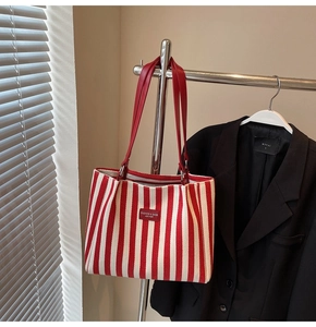 Détail d'un cabas en toile à rayures rouges et blanches avec anses en cuir robuste