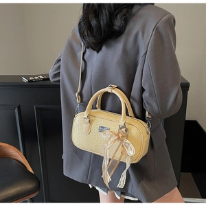 Vista dettagliata della borsa Boston gialla intrecciata con fiocco in pizzo crema e tracolla