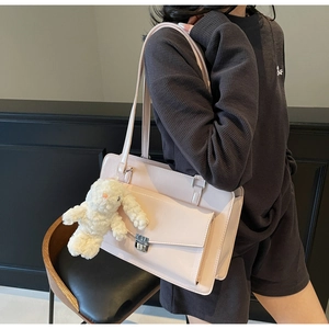 Détail du sac à main rose clair avec un charm lapin en peluche et un bouton pression