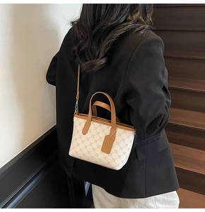 Détail d'un sac seau crème avec motifs géométriques et anses en cuir sur un mannequin