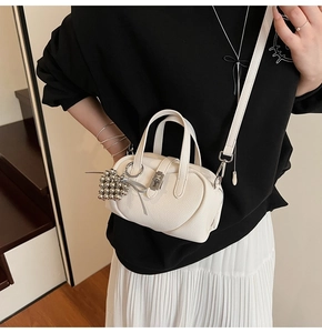 Mannequin portant un mini sac bandoulière en cuir crème avec fermoir argenté et breloque boule