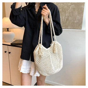 Close-up of cream handmade woven tote bag with hollow mesh pattern and side tassels