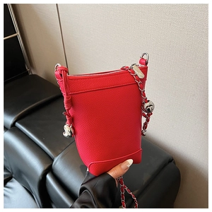 Gros plan du mini sac seau en cuir rouge avec breloque cœur et bandoulière chaîne