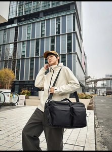 Gros plan d'un grand sac de voyage en nylon noir avec poches zippées et bandoulière réglable