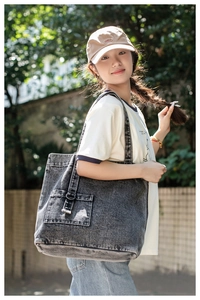 Detail of washed grey denim tote bag with external pocket and decorative buckle strap