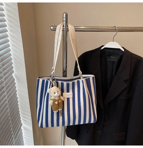 Détail du sac cabas en toile à rayures bleues avec un joli pendentif ours en peluche