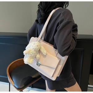 Détail latéral d'un sac cabas rose avec boucle argentée et breloque lapin en peluche