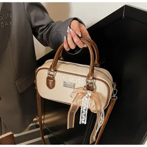 Dettaglio della borsa Boston crema con trama intrecciata e fiocco decorativo in pizzo