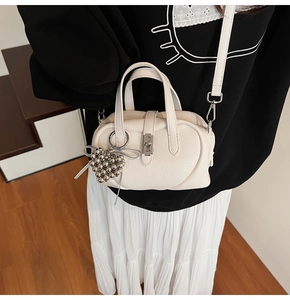 Gros plan du sac oreiller en cuir blanc crème avec breloque cœur en métal argenté