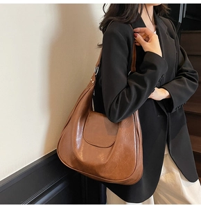 Side view of a vintage brown leather dumpling bag worn on shoulder for a retro style