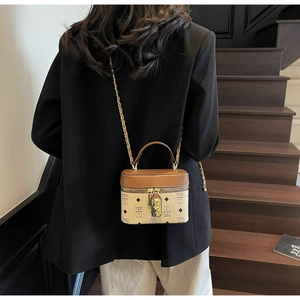 Detail of a mini bucket bag with bear print, metal lock, and chain strap worn by a model