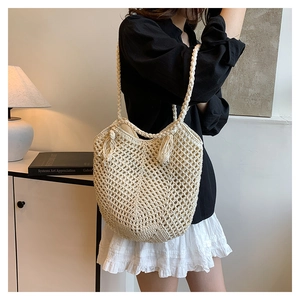 Macro detail of cream woven tote bag with hollow-out mesh design and fringe tassel decor