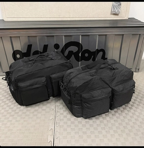 Détail de grands sacs de voyage noirs et gris à carreaux avec plusieurs poches et anses renforcées