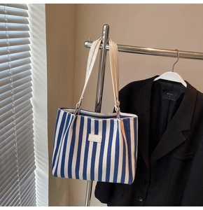 Détail du sac cabas en toile à rayures bleues et blanches avec écusson mode en cuir