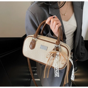 Dettaglio della borsa Boston con texture intrecciata, manici a contrasto e fiocco in pizzo