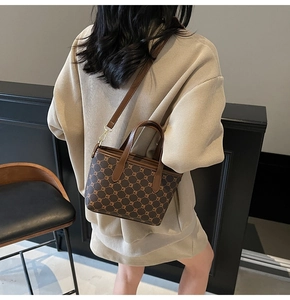 Détail d'un sac cabas marron à monogramme avec poignées en cuir et bandoulière amovible
