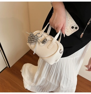 Gros plan d'un sac oreiller en cuir blanc avec charmant pendentif coeur en perles argent