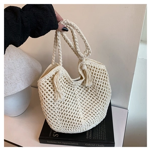 Detail of hollowed mesh texture and tassels on beige woven summer tote bag