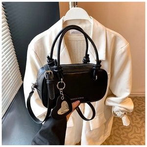 Détail du sac à main noir en similicuir avec poignée nouée et pendentif cœur