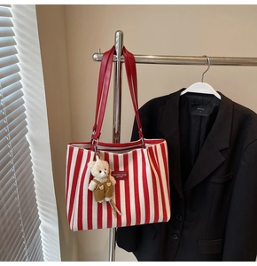 Détail du sac fourre-tout rayé rouge avec anses en cuir et pendentif ours mignon