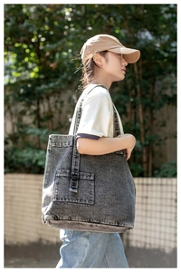 Detailed view of the dark grey washed denim tote bag with cargo pockets and buckled straps