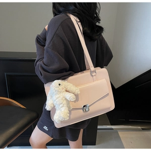 Détail d'un cabas en cuir rose avec breloque lapin et boucle en métal sur tenue