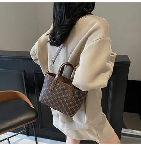 Détail du sac seau marron vintage avec monogramme, poignées en cuir et bandoulière