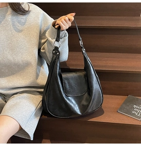 Detail of glossy black leather hobo bag with sleek silver metal ring hardware