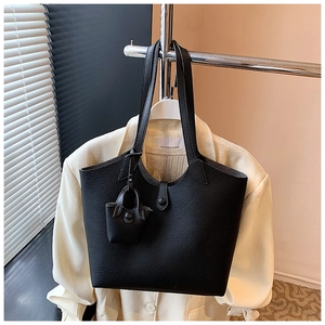 Detail of black pebbled leather tote bag with mini pouch on a white blazer