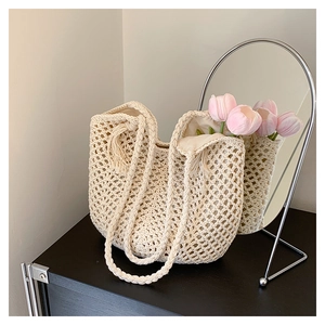 Detail of hand-woven cream tote bag with fringe charm and braided strap in a cozy interior