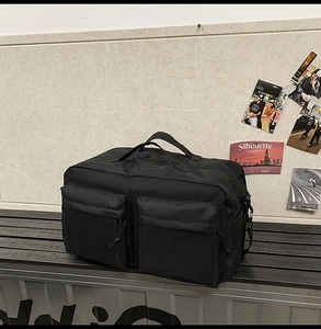 Vue détaillée du sac de voyage en nylon noir avec grandes poches avant sur un banc